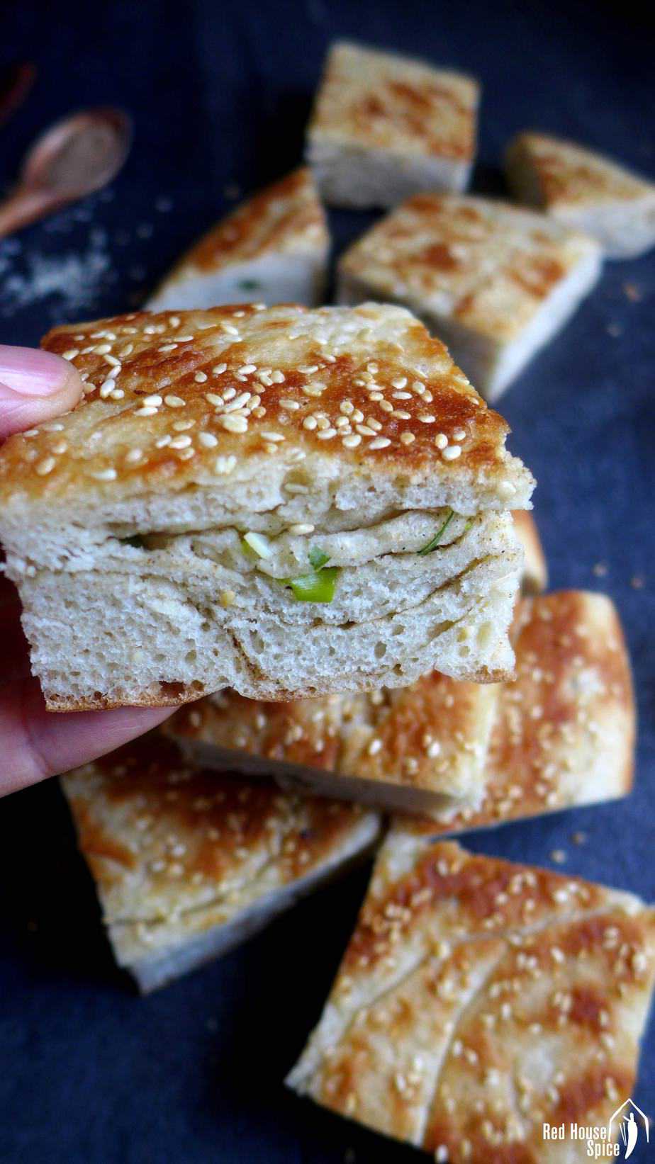 A piece of leavened scallion flatbread held by a hand