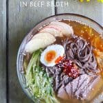 A bowl of cold soba noodles in beef broth, topped with cucumber, apple and hard-boiled egg.
