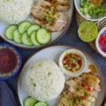 two plateful of hainanese chicken rice with seasonings on the side