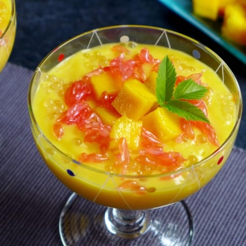 A dessert glass filled with mango puree and grapefruit pieces