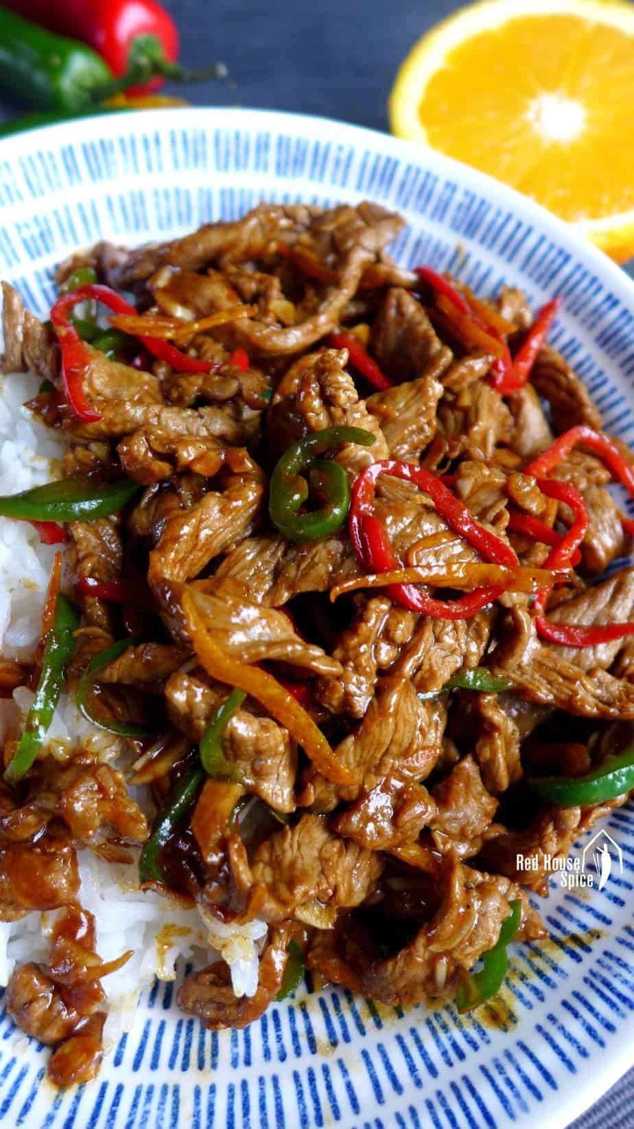 A plate of stir-fried orange beef over rice