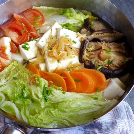 A pot of tofu soup with various vegetables
