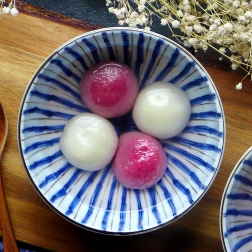 White and pink Tang Yuan (Chinese glutinous rice balls) in serving bowls.
