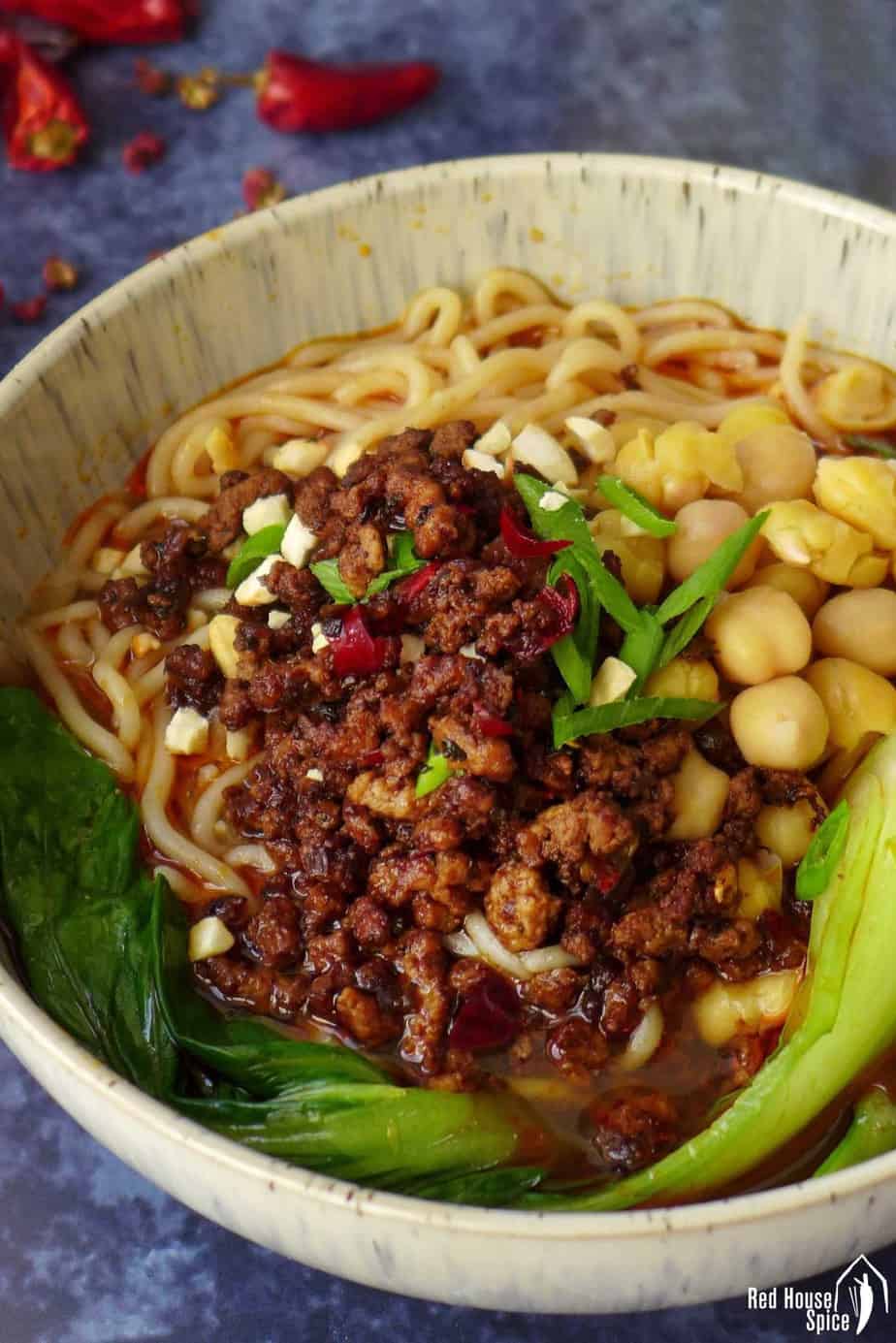 A bowl of Chongqing noodles topped with minced meat and chickpeas.