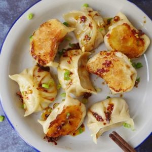 A plate of vegan dumplings covered with spicy sauce