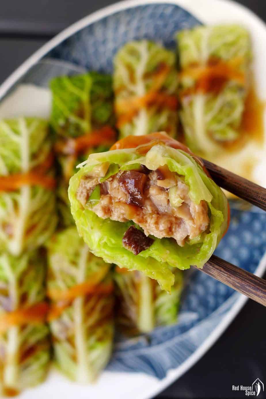 A steamed cabbage roll held by chopsticks.