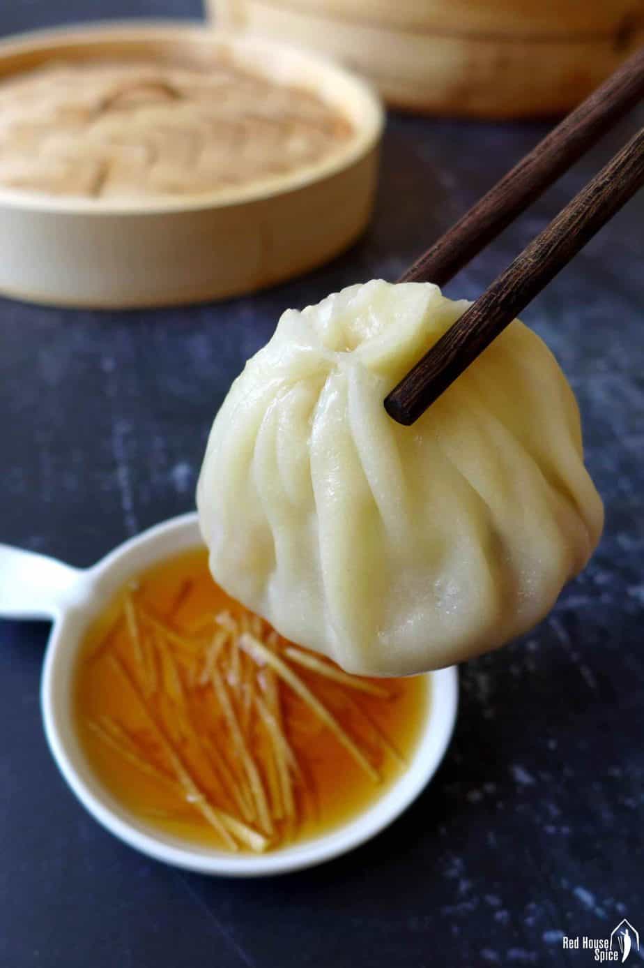 A soup dumpling picked up by a pair of chopsticks