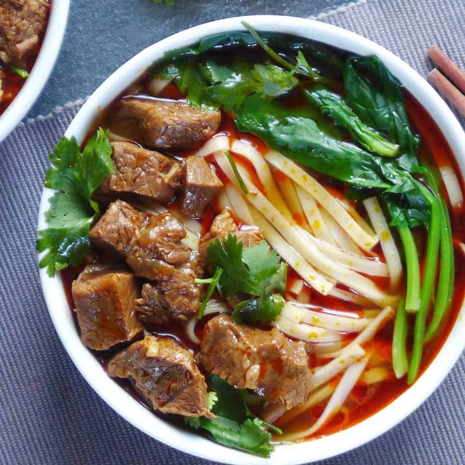 A bowl of noodle soup topped with beef cubes