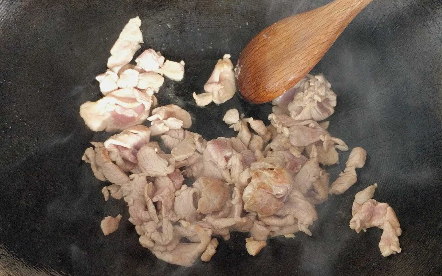 Frying pork slices in a wok