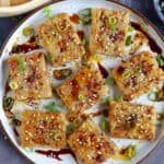 Turnip cake dressed with sesame seeds, scallions, soy sauce & chili oil
