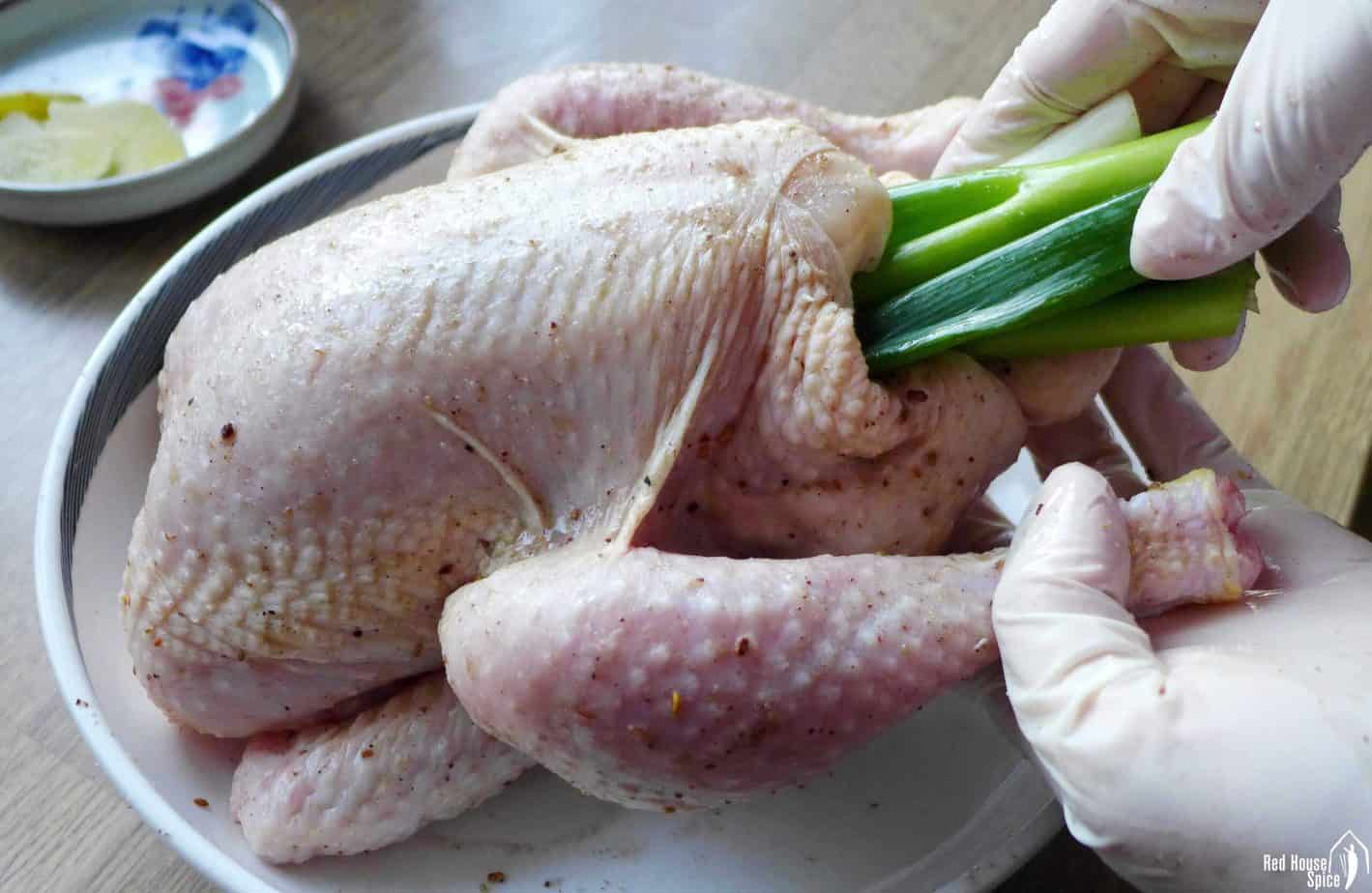 Putting scallions into the cavity of a chicken