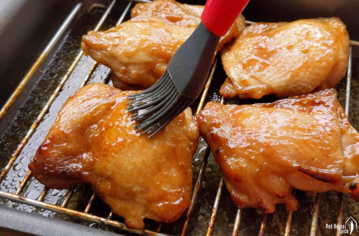 brushing sauce over chicken thighs