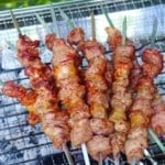 Cooking lamb skewers over charcoal with overlay text that says Chinese lamb skewers