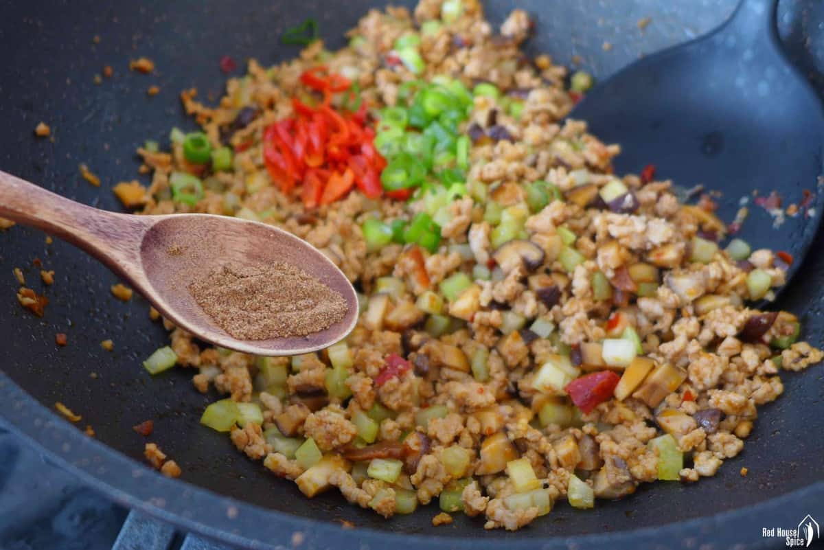 adding ground Sichuan pepper to stir fried pork and veggies.