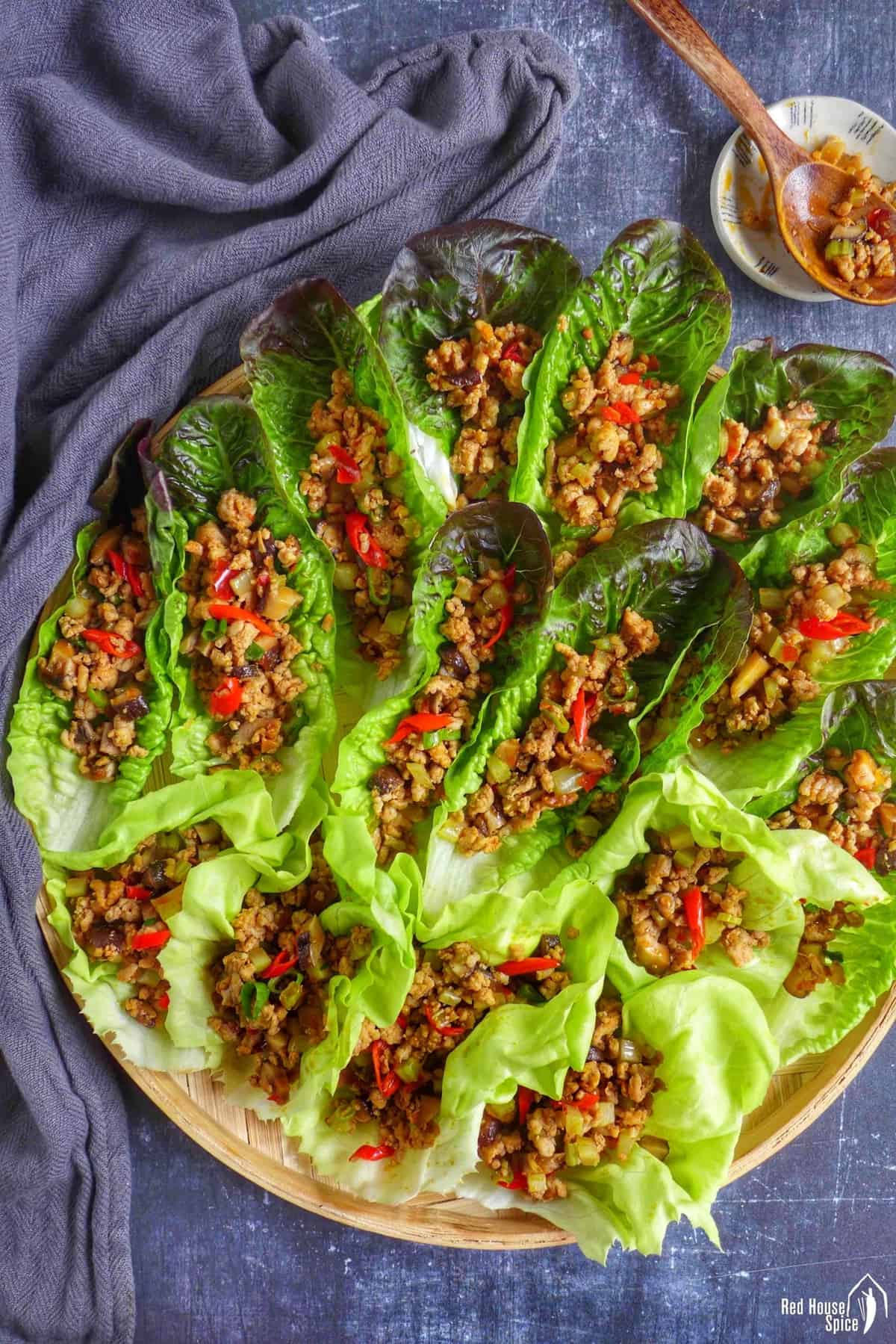 Lettuce wraps with pork fillings on a tray.