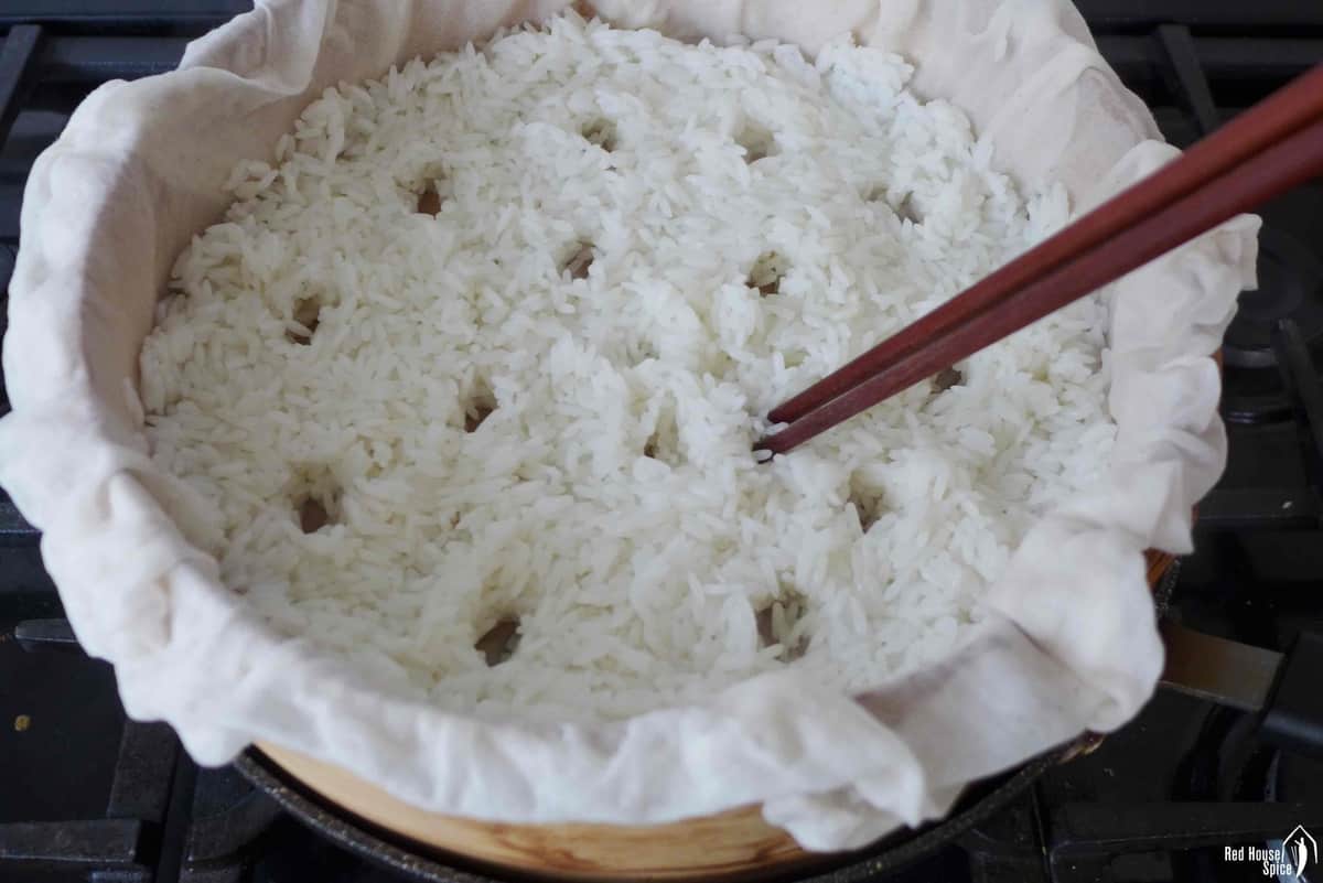 Poking holes in rice inside a steamer.