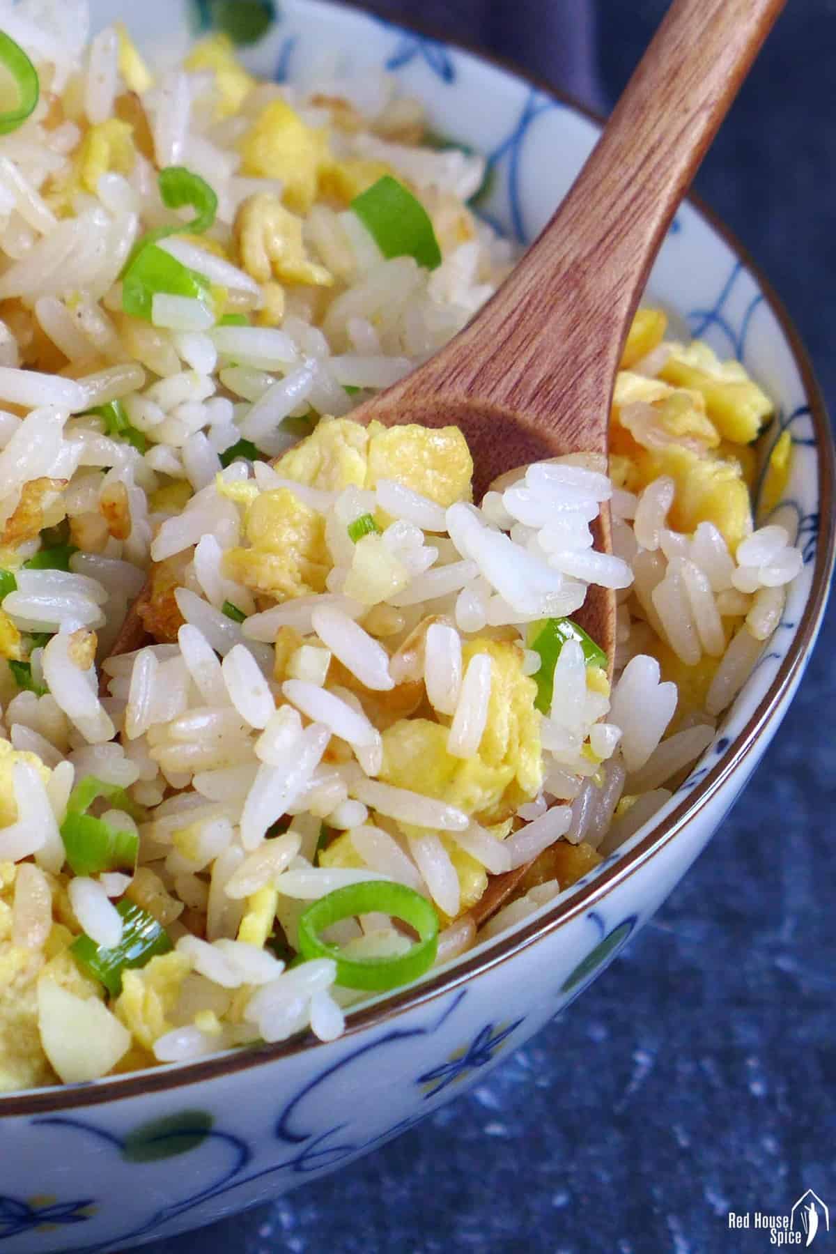 Scooping out egg fried rice with a spoon.