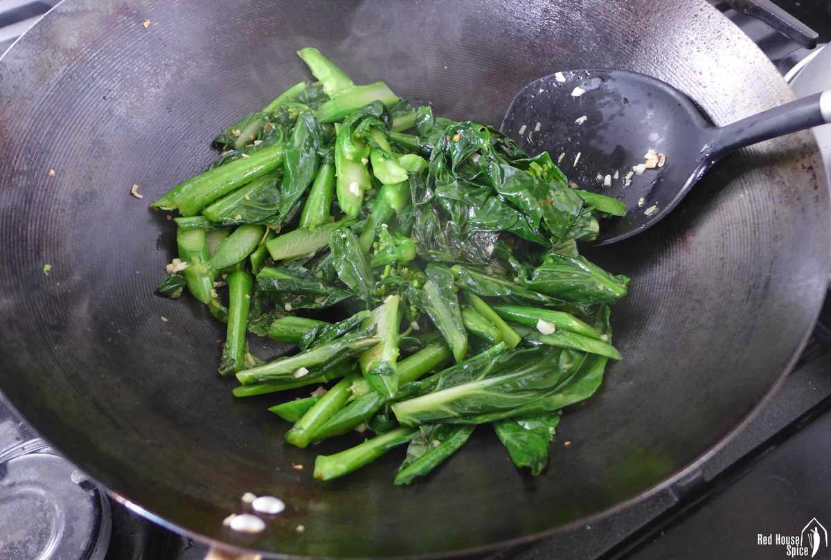 stir frying chinese broccoli in a wok.