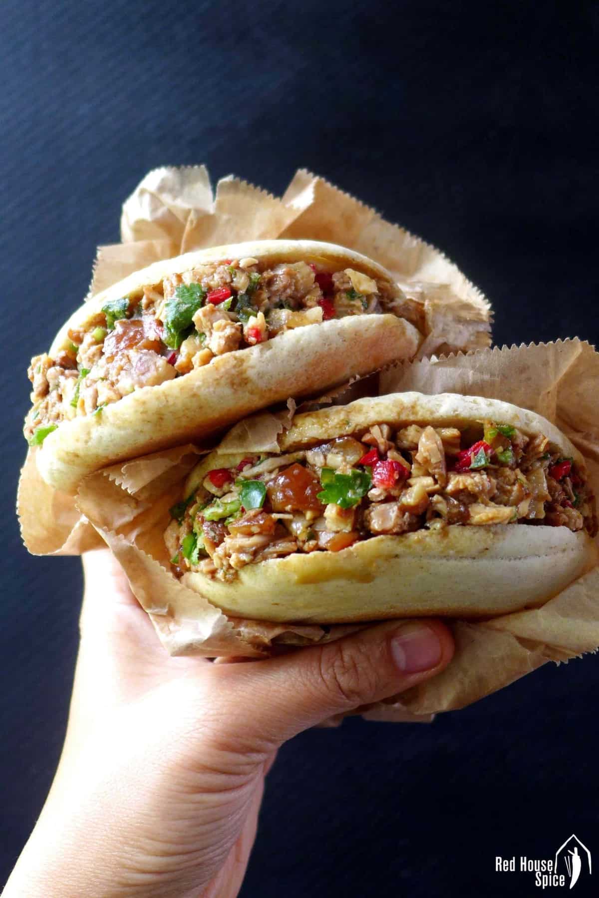 Two chinese pork burgers held by a hand