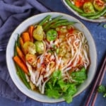 A bowl of noodle soup with turkey and vegetables