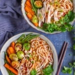 Two bowls of noodle soup made with Christmas leftovers, such as shredded turkey, Brussels sprouts, carrots and green beans.