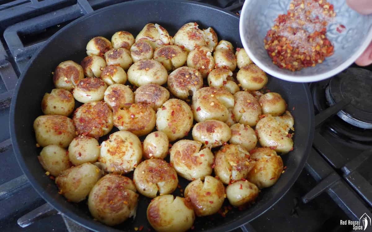Adding spices to pan-fried baby potatoes