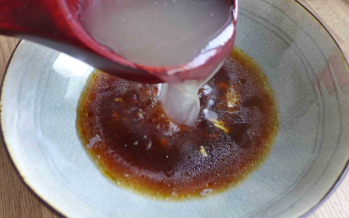 Adding stock to sauce in a bowl