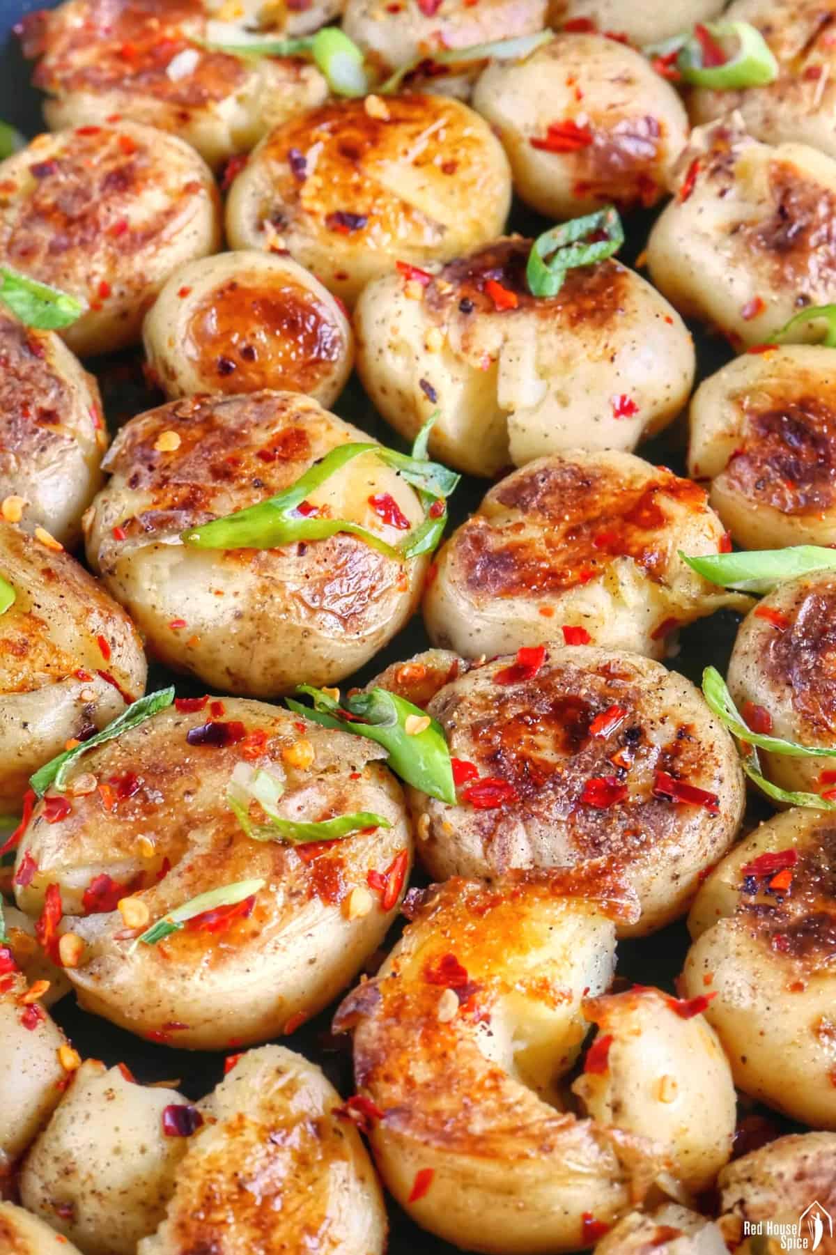 Golden pan-fried baby potatoes garnished with spices and scallions