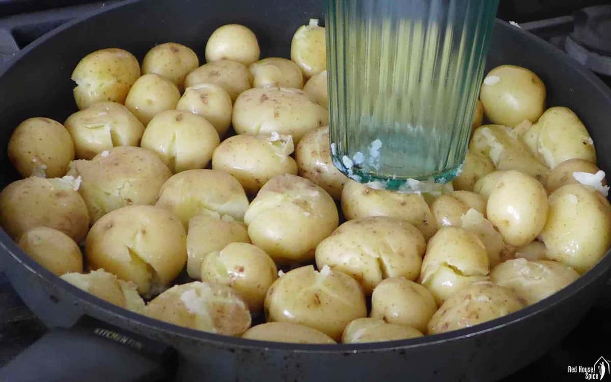 Crushing cooked baby potatoes with a glass