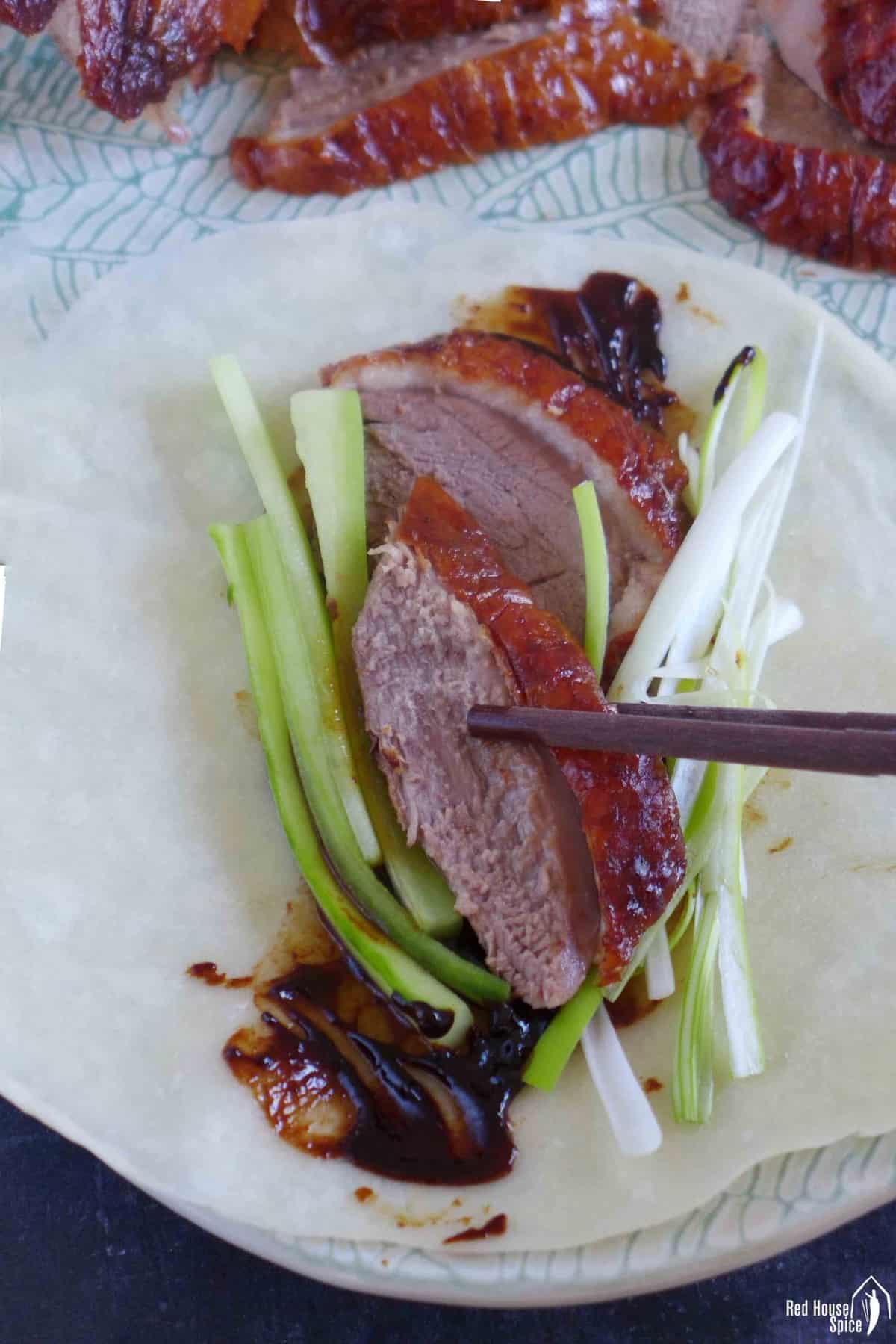 two slices of duck and vegetables on a thin pancake.