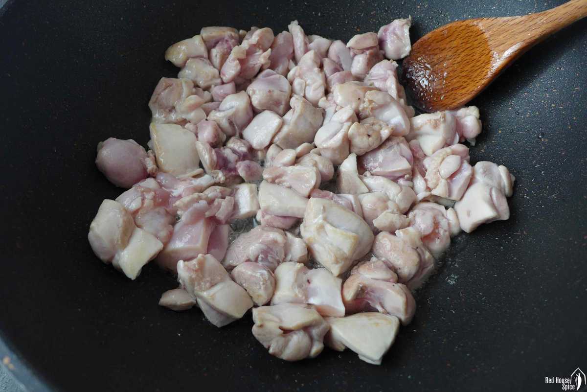 Searing chicken pieces in a wok