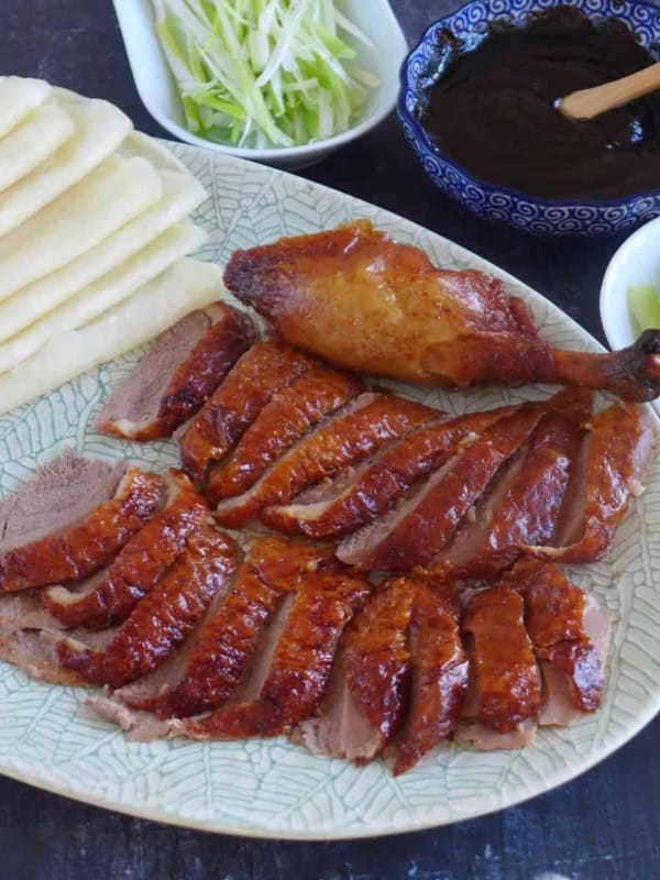 Sliced Peking duck with thin pancakes, dark sauce, and julienned vegetables