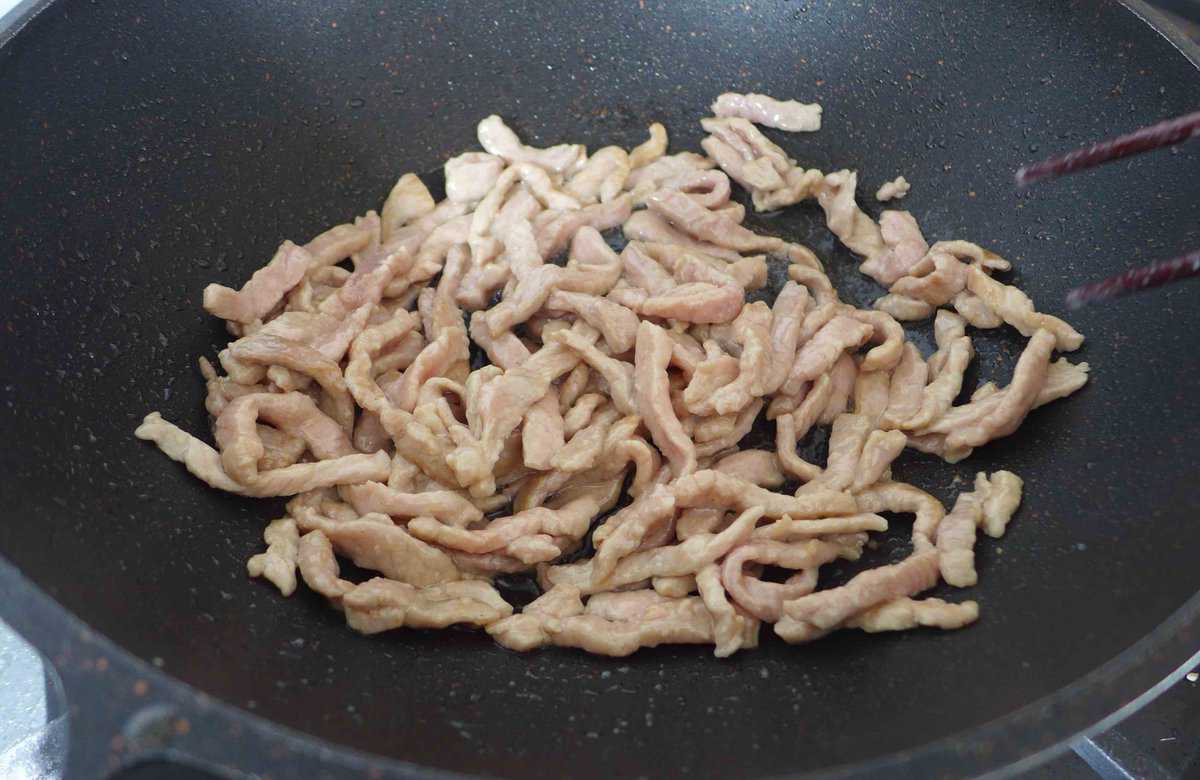 frying pork strips in a wok
