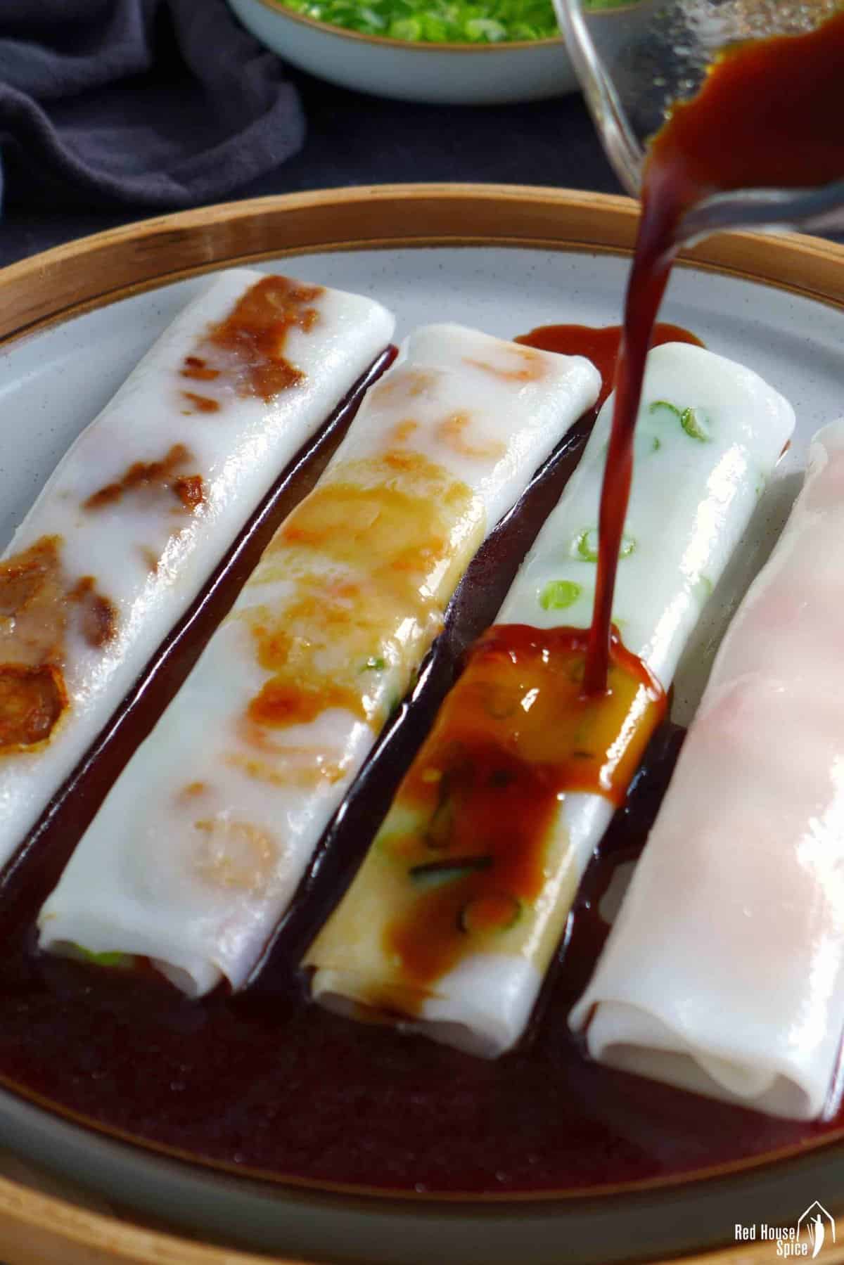 pouring sauce over steamed rice noodle rolls