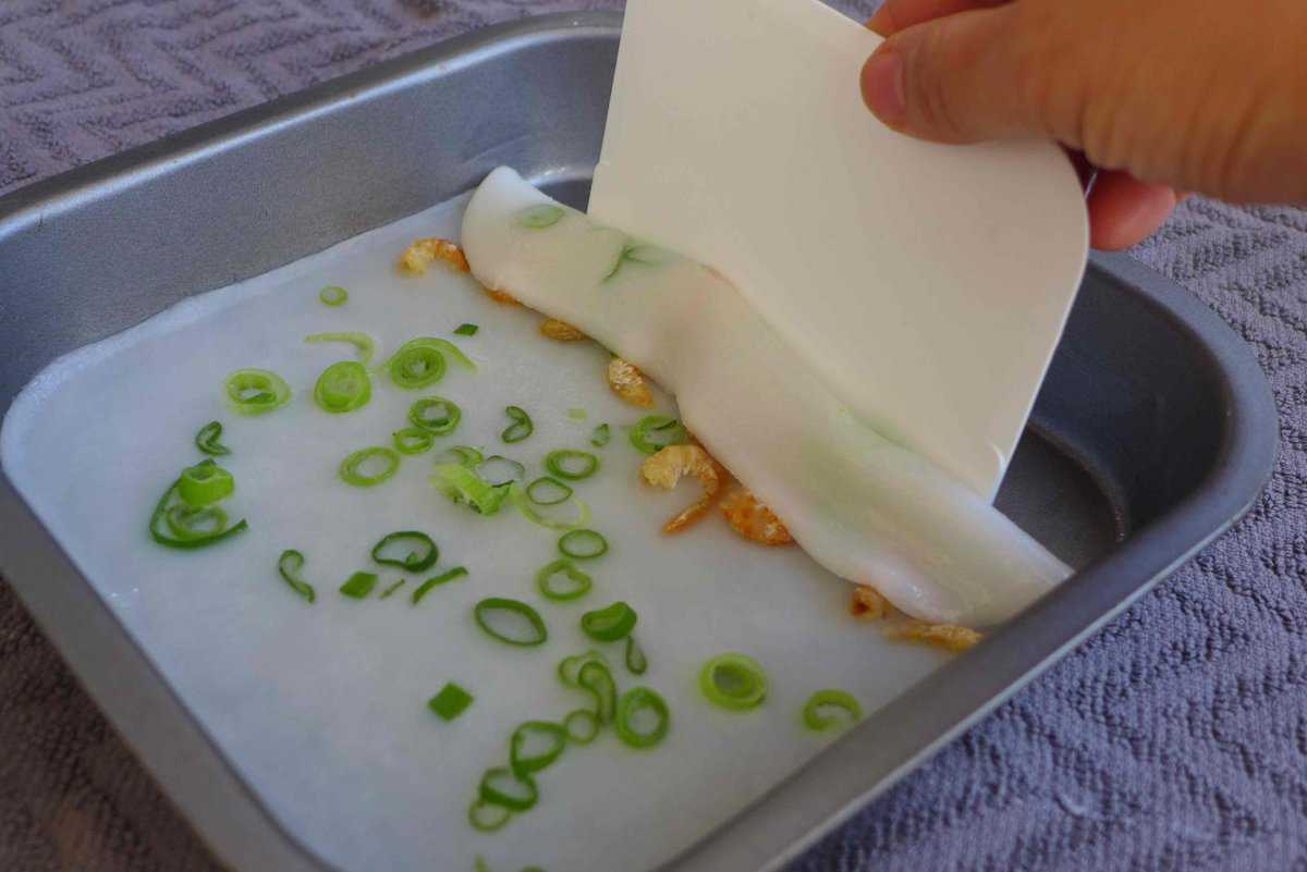 scrapping rice noodle off a tray