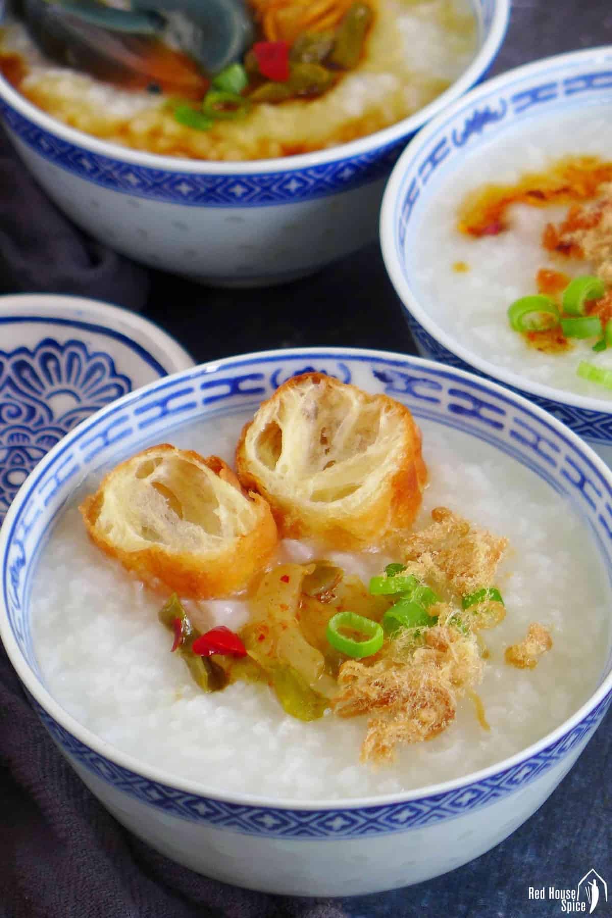 three bowls of plain congee with different toppings