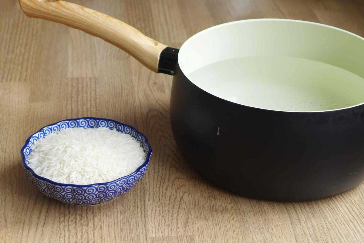 a bowl of raw rice with a pot of water