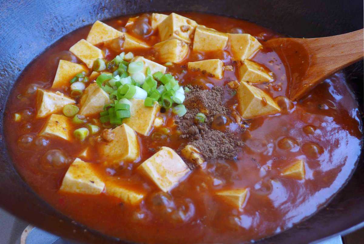 adding Sichuan pepper and scallions to Mapo tofu