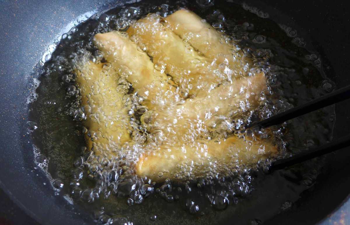 deep-frying spring rolls in a wok