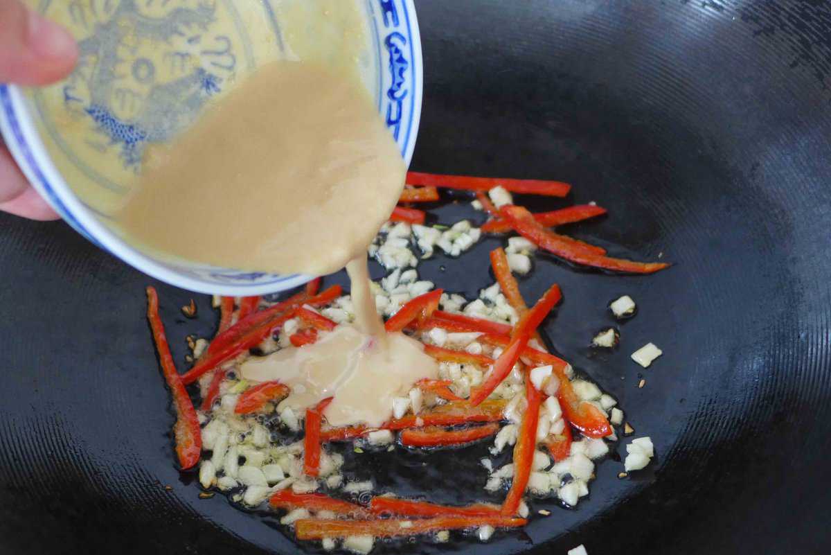 adding fermented tofu sauce to a wok