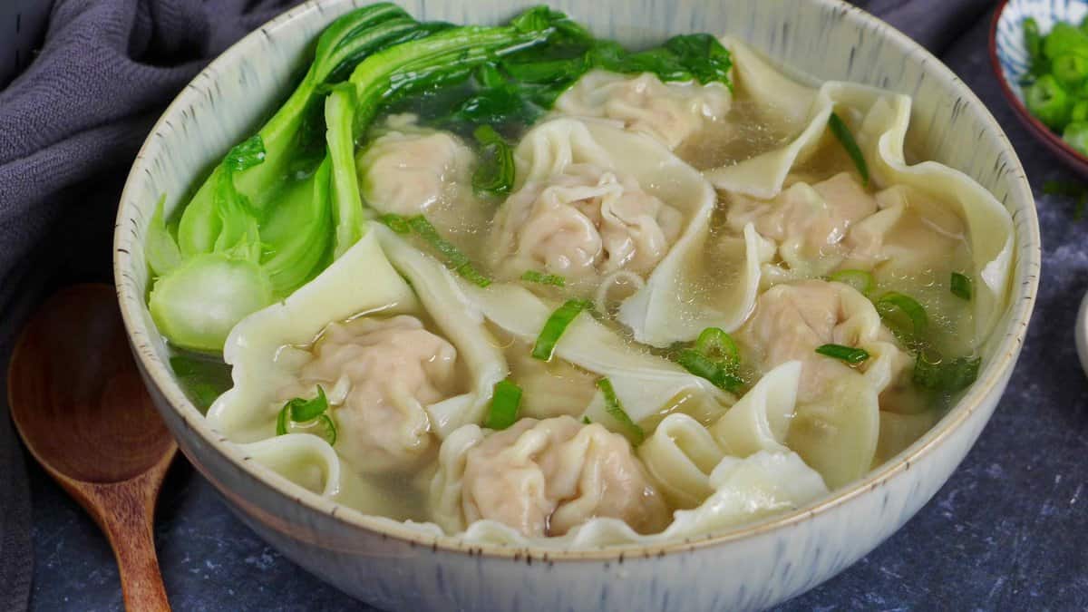 A bowl of wontons with soup and blanched Bok Choy.