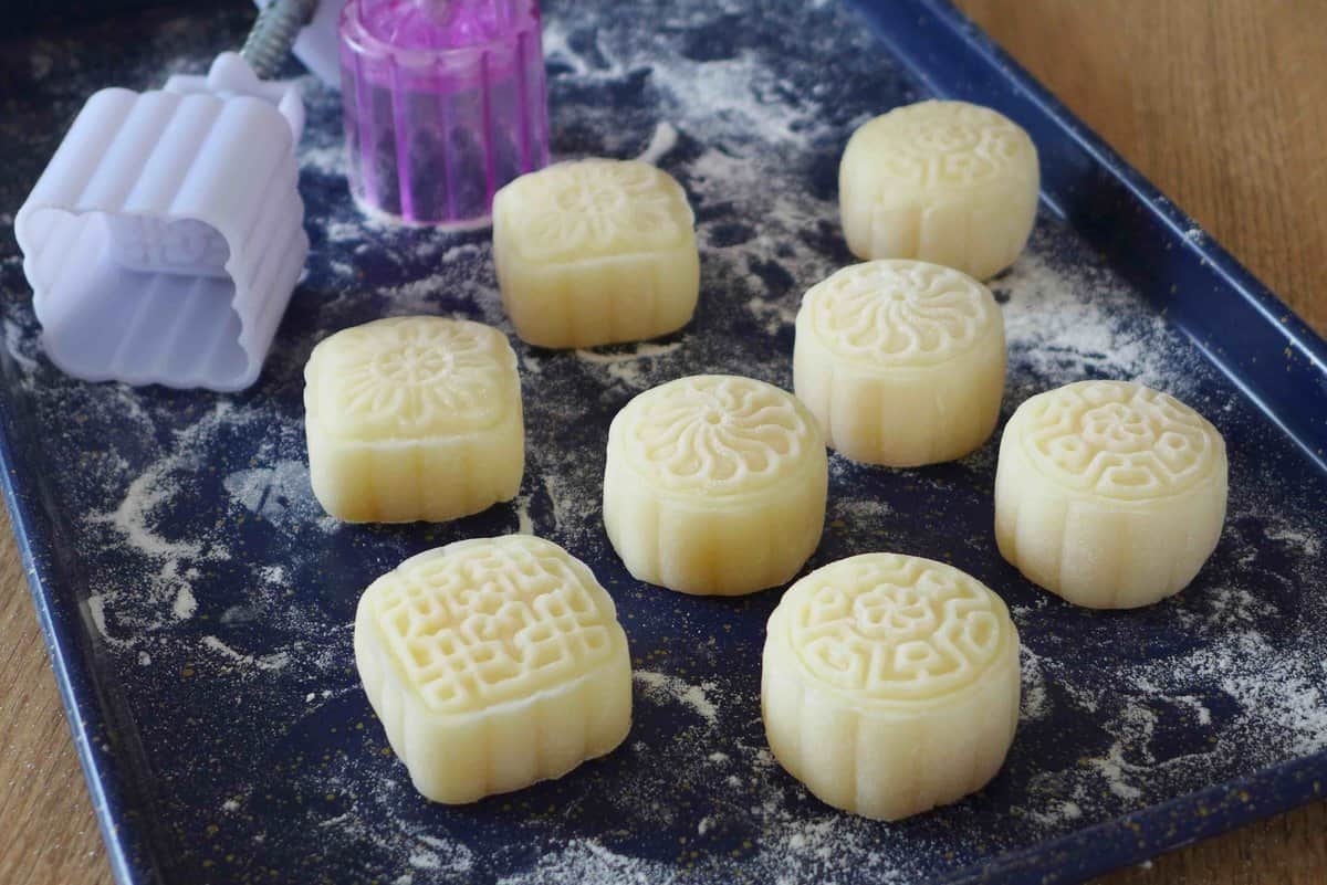 white mooncakes on a dusted tray.