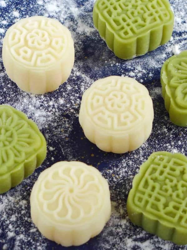 white and green Snow Skin Mooncakes on a dusted surface.
