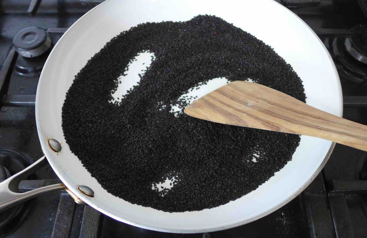 Toasting black sesame seeds in a pan.