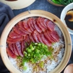 sliced chinese sausage over rice with sauce and scallions.