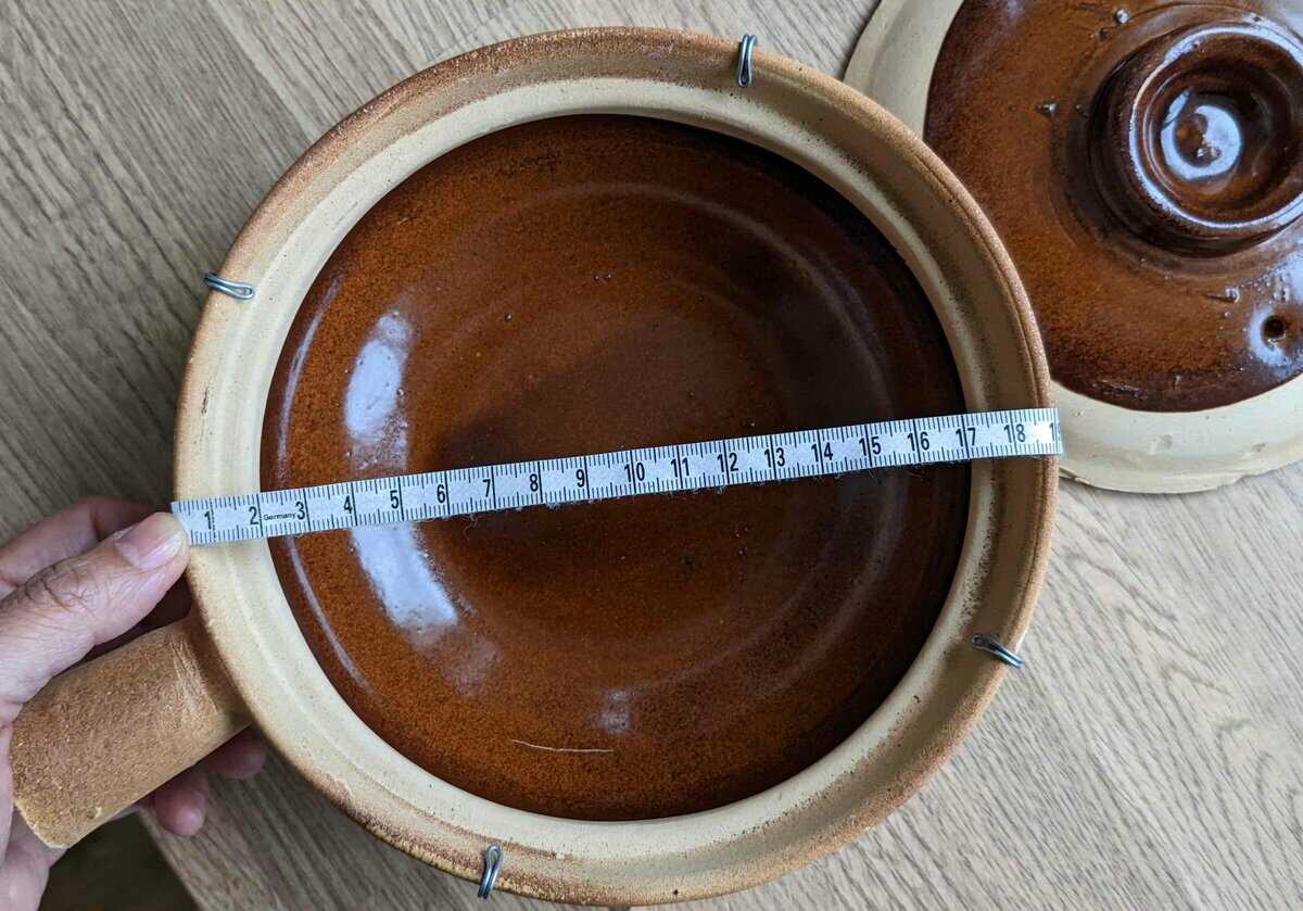 An empty chinese clay pot with a measuring tape.