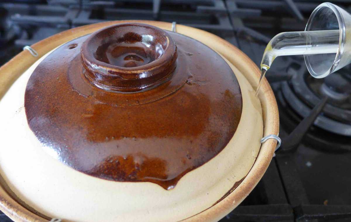 pouring oil into a clay pot.