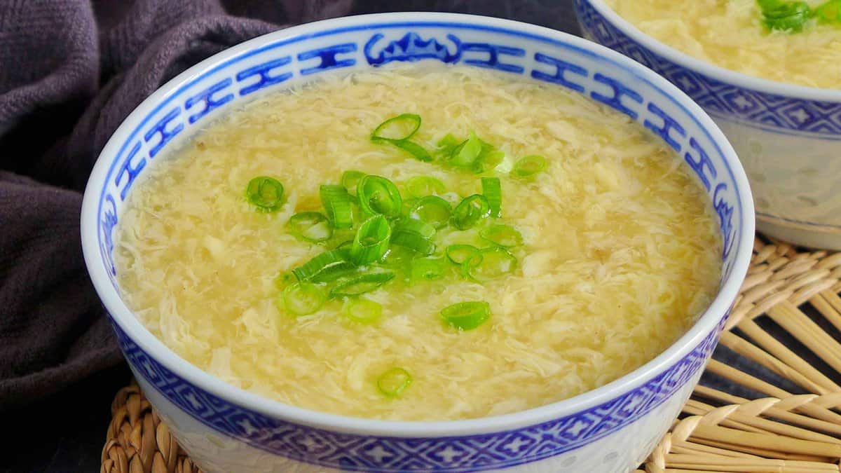 A bowl of egg drop soup garnished with spring onion.
