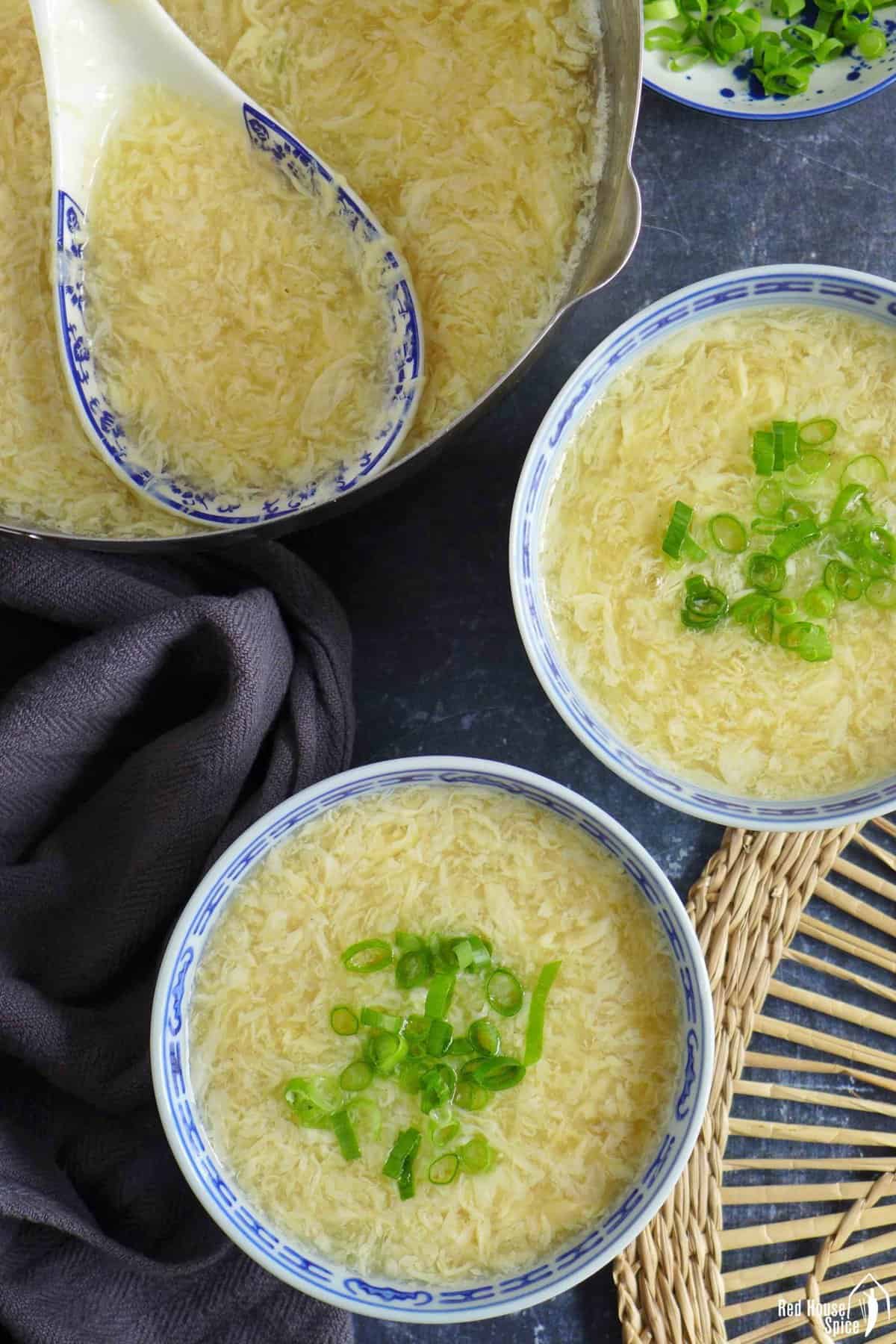 Egg drop soup in pot and bowls.
