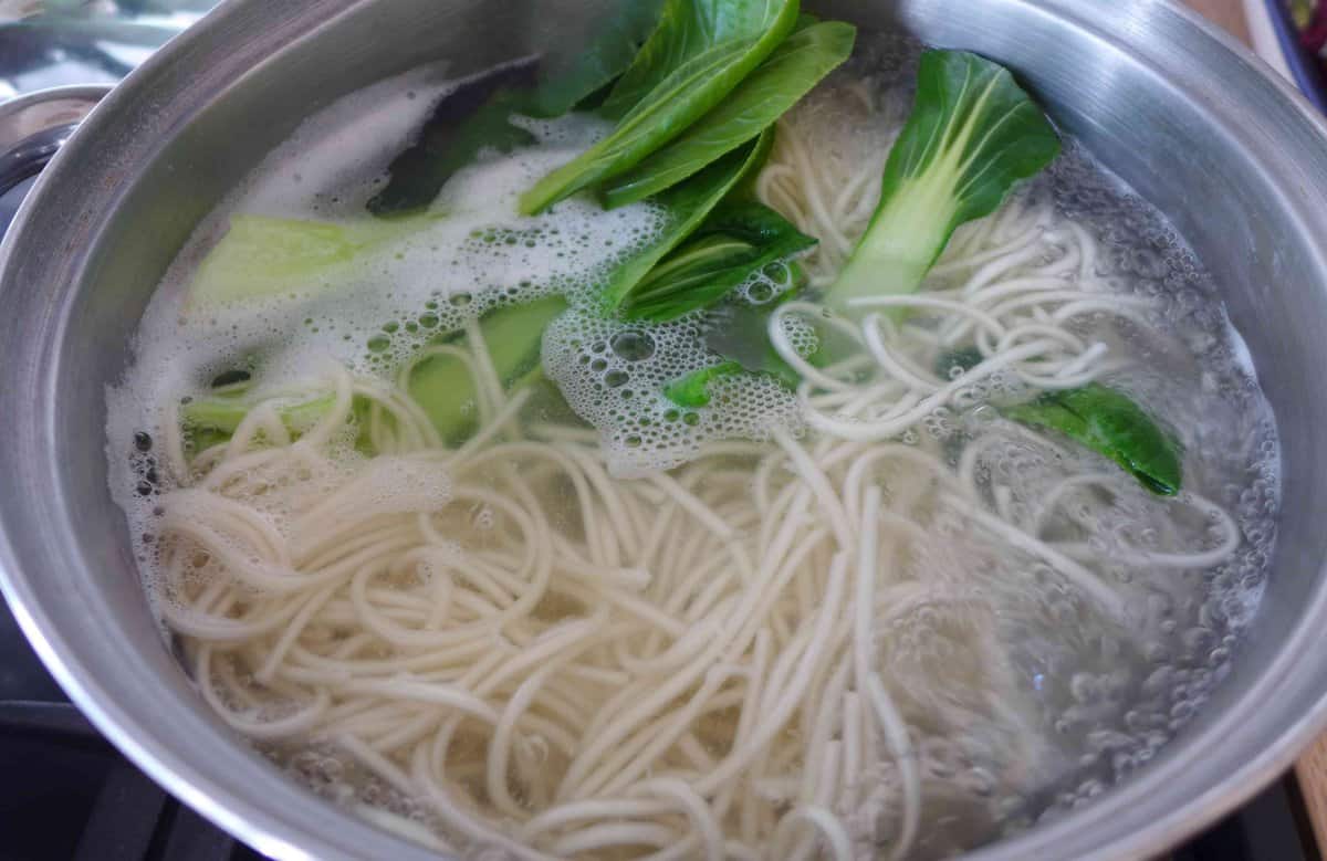 boiling noodles and Bok Choy in water.